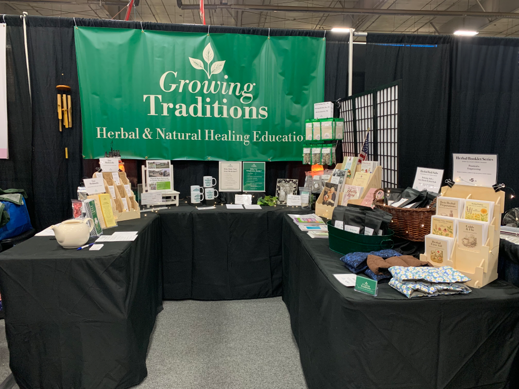 Herbal Education at the County Fair booth display at the 2025 Lancaster County Super Fair, featuring Growing Traditions banner, educational bookmarks and handouts, herbal products, mugs, bath salts and five new herbal booklets.